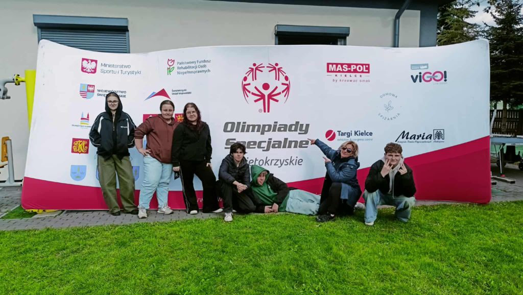 Członkowie szkolnego Wolontariatu na tle baneru Olimpiad Specjalnych